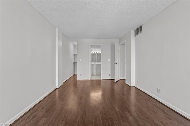 unfurnished living room with dark wood-type flooring and a textured ceiling