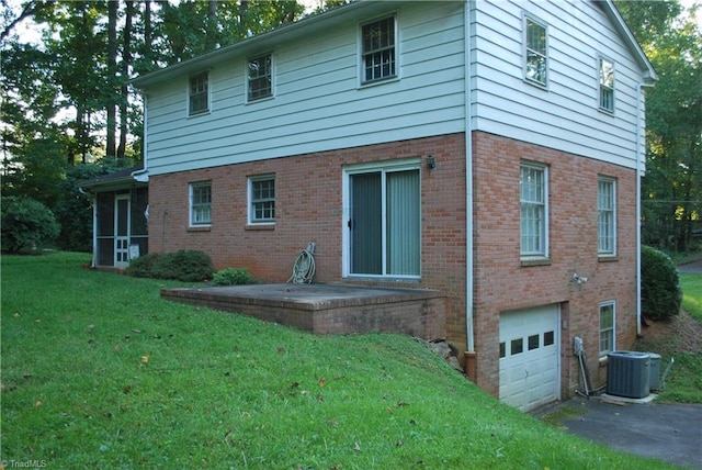 rear view of property featuring a garage, a lawn, and central air condition unit