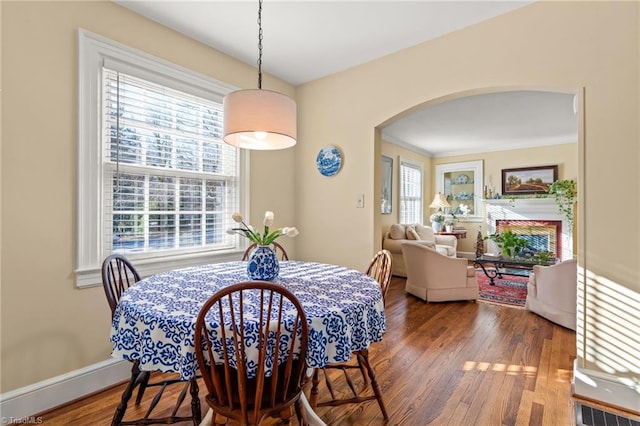 dining space featuring a healthy amount of sunlight, wood-type flooring, and crown molding