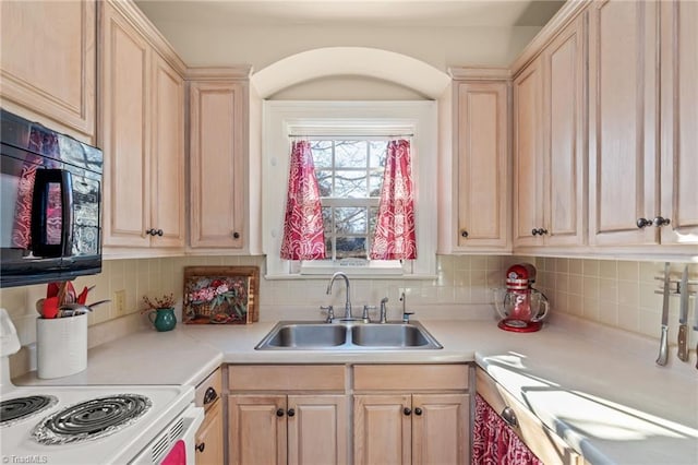 kitchen with stove, sink, light brown cabinetry, and tasteful backsplash