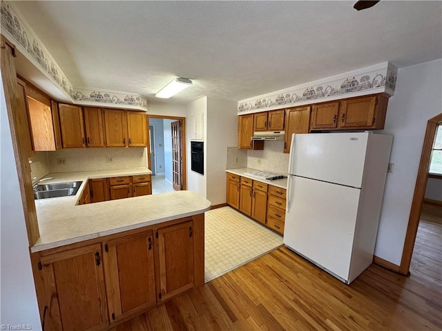 kitchen featuring kitchen peninsula, white appliances, sink, light tile floors, and backsplash