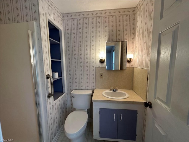 bathroom with toilet, vanity with extensive cabinet space, and tile flooring