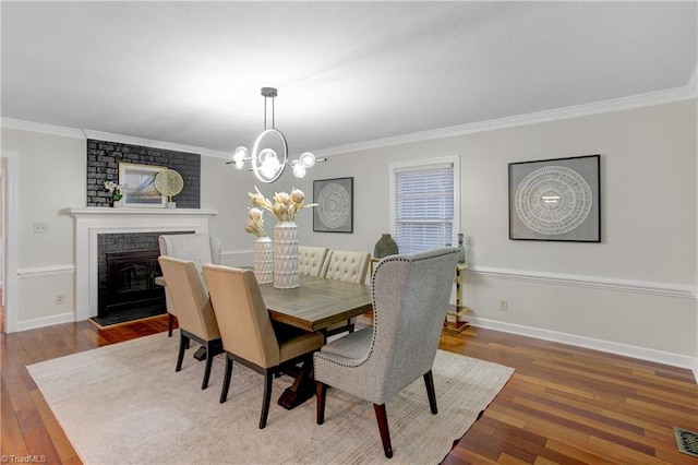 dining room with a fireplace, hardwood / wood-style flooring, an inviting chandelier, and ornamental molding