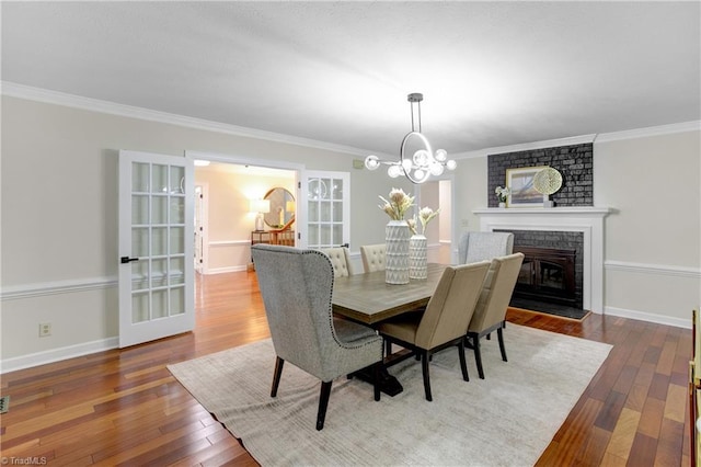 dining room featuring a chandelier, hardwood / wood-style flooring, a brick fireplace, and ornamental molding