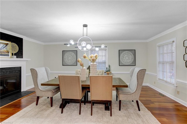 dining area featuring a wealth of natural light, a fireplace, ornamental molding, and hardwood / wood-style flooring