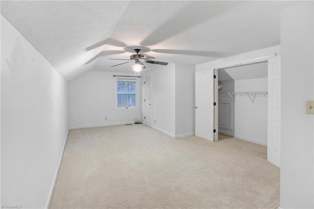 additional living space with light carpet, a textured ceiling, ceiling fan, and lofted ceiling