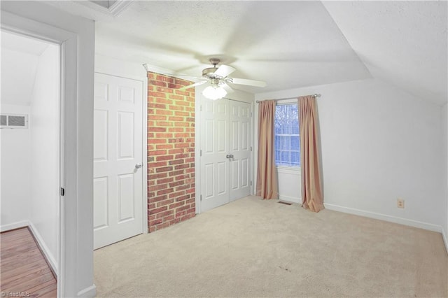 unfurnished bedroom with a textured ceiling, ceiling fan, light carpet, and lofted ceiling