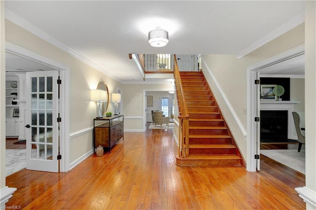 staircase with hardwood / wood-style floors and ornamental molding