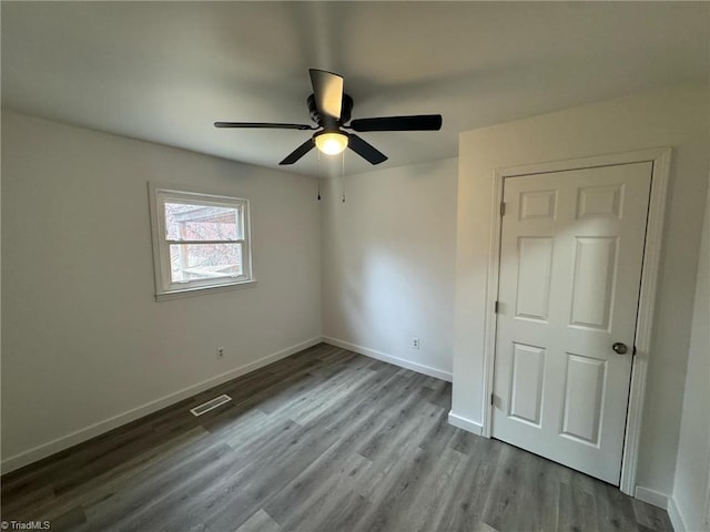 unfurnished bedroom with a ceiling fan, baseboards, visible vents, and wood finished floors