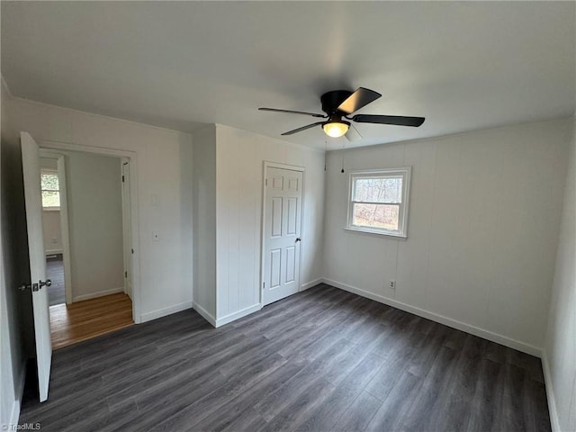 unfurnished bedroom with a closet, dark wood finished floors, baseboards, and ceiling fan