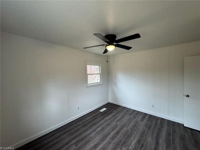 spare room featuring dark wood-type flooring, baseboards, and a ceiling fan