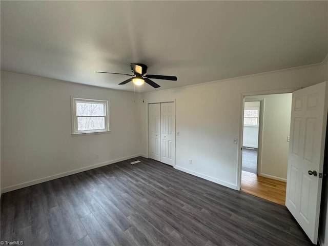 unfurnished bedroom featuring a ceiling fan, baseboards, dark wood finished floors, and a closet