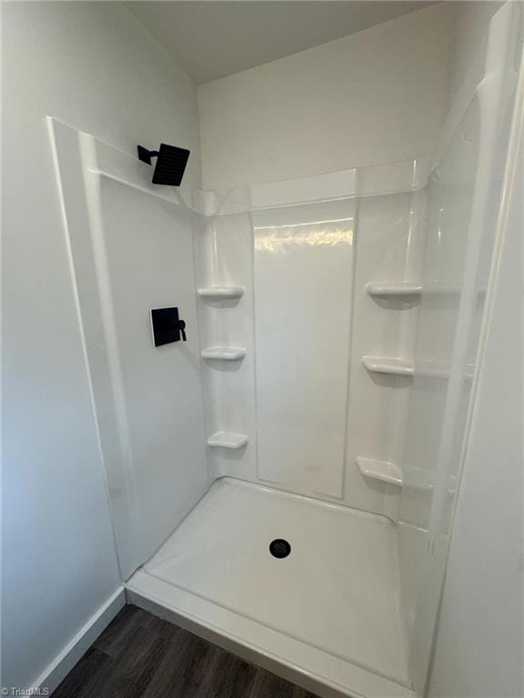 full bathroom featuring walk in shower, baseboards, and wood finished floors