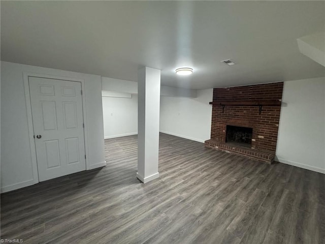 finished basement featuring dark wood-style flooring, visible vents, a fireplace, and baseboards