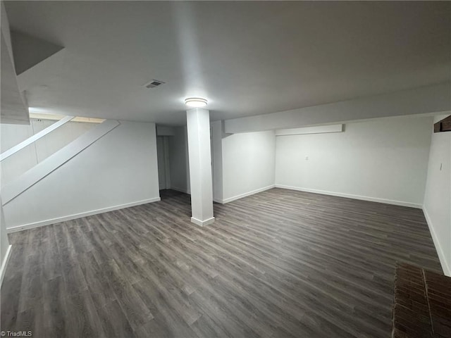 finished below grade area featuring dark wood-style floors, visible vents, and baseboards