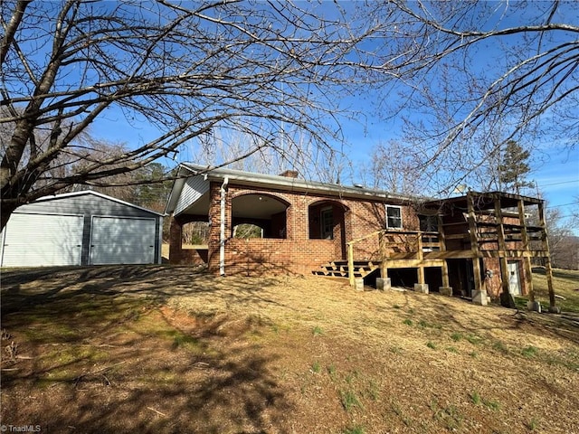 rear view of property featuring an outbuilding, brick siding, a detached garage, a chimney, and a deck