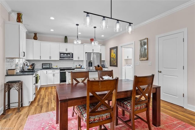 dining room with light wood-type flooring, crown molding, and recessed lighting