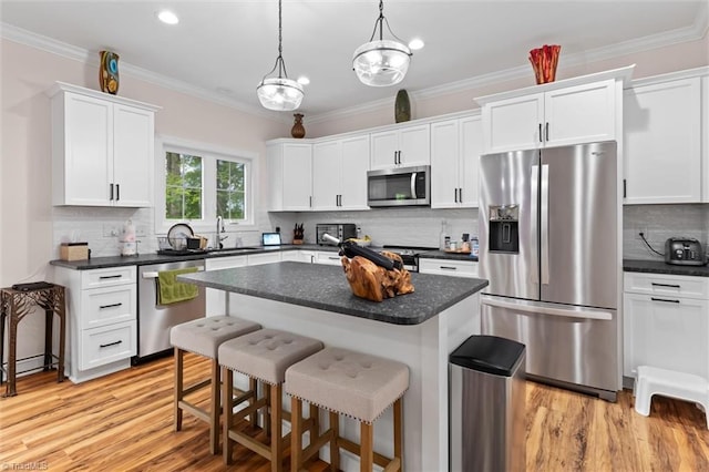 kitchen with stainless steel appliances, a kitchen bar, white cabinetry, dark countertops, and tasteful backsplash