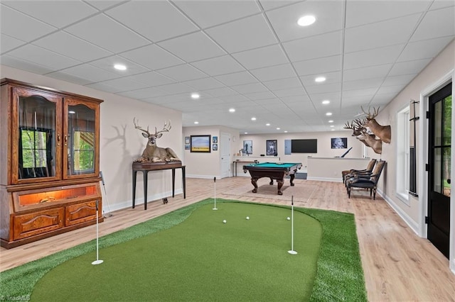 game room with light wood-type flooring, a putting area, a paneled ceiling, baseboards, and recessed lighting