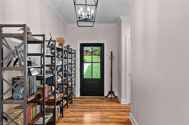 foyer entrance with a chandelier, wood finished floors, ornamental molding, and baseboards
