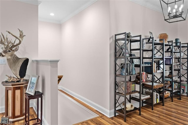 corridor featuring an upstairs landing, wood finished floors, ornamental molding, baseboards, and a chandelier