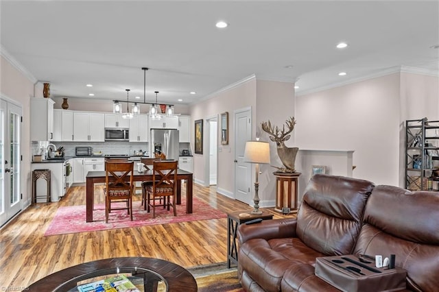 living area with light wood-style flooring, crown molding, recessed lighting, and baseboards