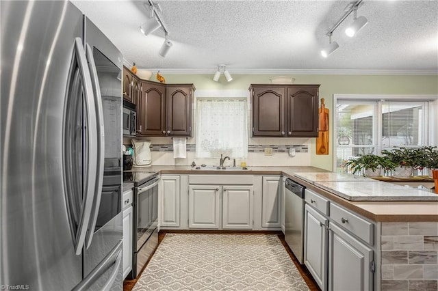 kitchen with kitchen peninsula, backsplash, a textured ceiling, stainless steel appliances, and sink