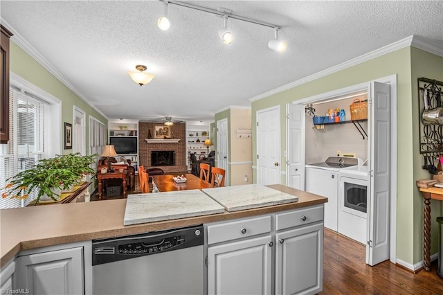 kitchen with a brick fireplace, stainless steel dishwasher, a textured ceiling, washer and clothes dryer, and dark hardwood / wood-style floors