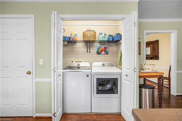 clothes washing area with crown molding, washer and clothes dryer, dark hardwood / wood-style floors, and a textured ceiling