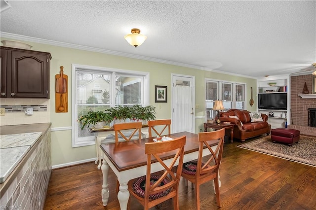 dining area with a textured ceiling, crown molding, dark hardwood / wood-style floors, and a brick fireplace