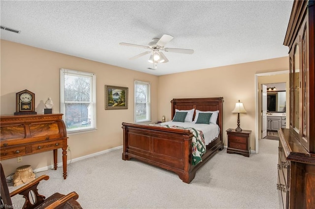 bedroom with ensuite bathroom, ceiling fan, light colored carpet, and a textured ceiling