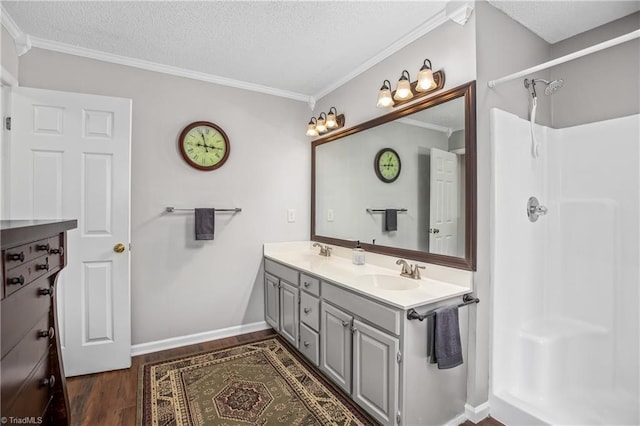 bathroom featuring a shower, wood-type flooring, a textured ceiling, vanity, and ornamental molding