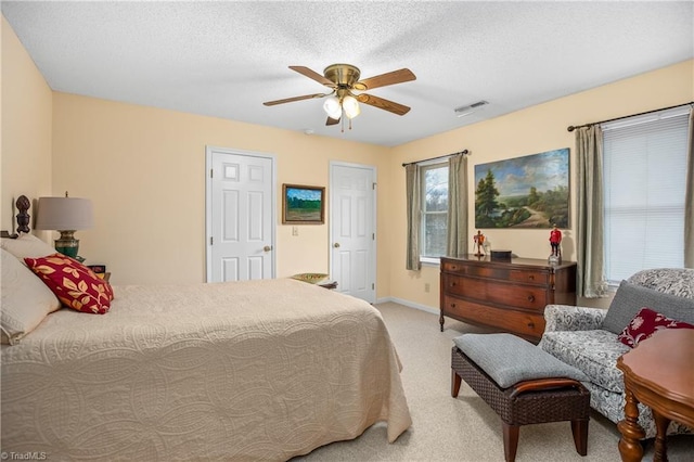 bedroom with ceiling fan, light carpet, and a textured ceiling