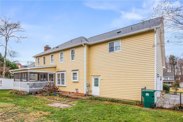 rear view of property with a yard and a sunroom