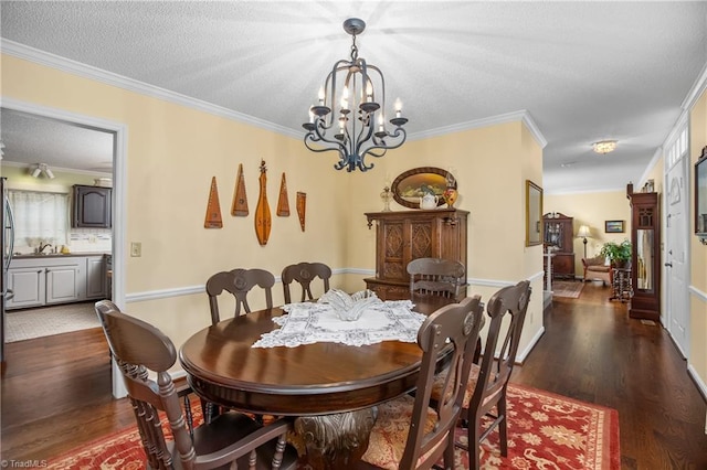 dining space with a textured ceiling, ornamental molding, dark wood-type flooring, and a chandelier