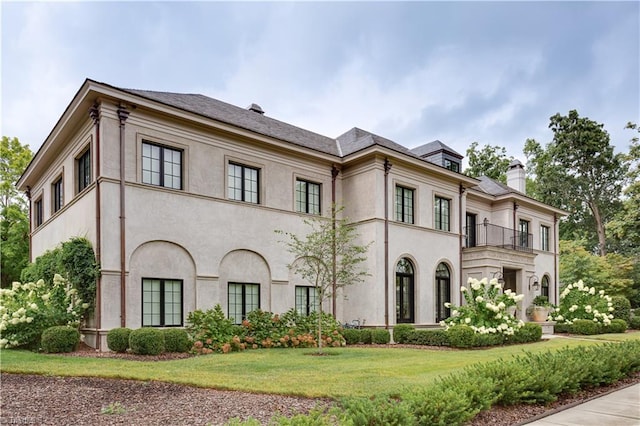 view of front of property featuring a front yard and a balcony