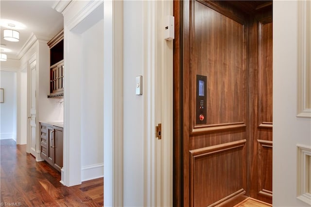 corridor with ornamental molding, dark hardwood / wood-style flooring, and elevator