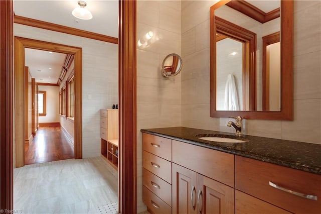 bathroom with vanity, crown molding, hardwood / wood-style floors, and tile walls