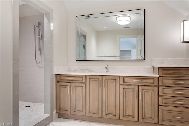 bathroom featuring vanity, vaulted ceiling, and tiled shower