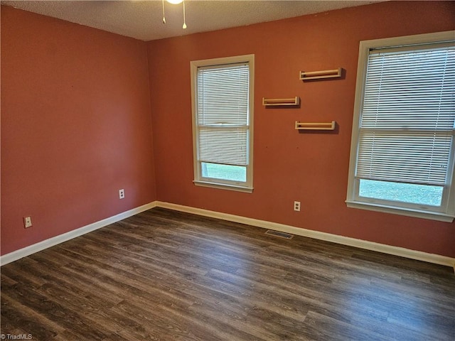 empty room with dark wood-type flooring and a textured ceiling