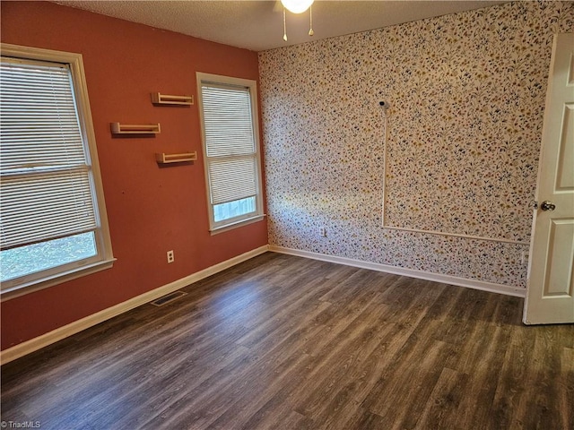 spare room featuring a textured ceiling and dark hardwood / wood-style floors