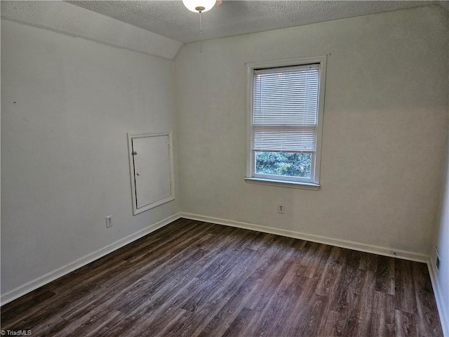 unfurnished room with a textured ceiling, dark hardwood / wood-style flooring, and vaulted ceiling