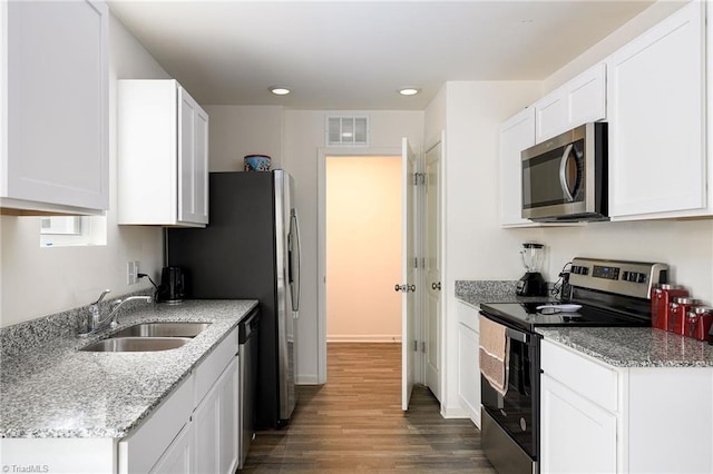 kitchen with stainless steel appliances, wood finished floors, a sink, visible vents, and white cabinets