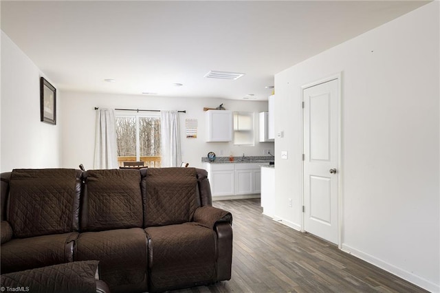 living area with dark wood-type flooring, visible vents, and baseboards