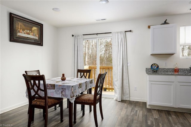 dining space with dark wood-style floors, visible vents, and baseboards