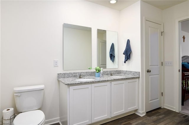 bathroom with double vanity, a sink, toilet, and wood finished floors