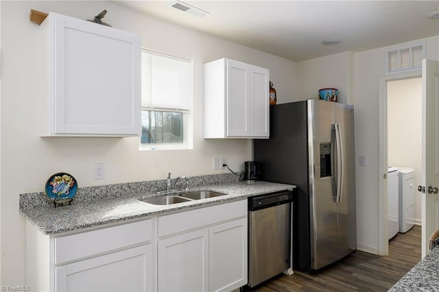 kitchen featuring visible vents, white cabinets, appliances with stainless steel finishes, washer and dryer, and a sink