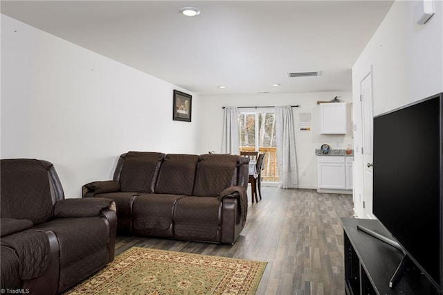 living area with recessed lighting, visible vents, and wood finished floors