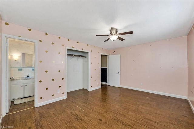unfurnished bedroom featuring connected bathroom, a sink, a closet, baseboards, and wood finished floors