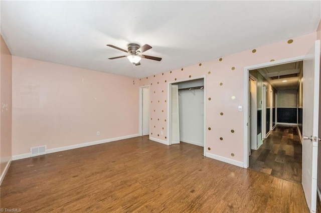 unfurnished bedroom with wood finished floors, visible vents, a closet, and baseboards